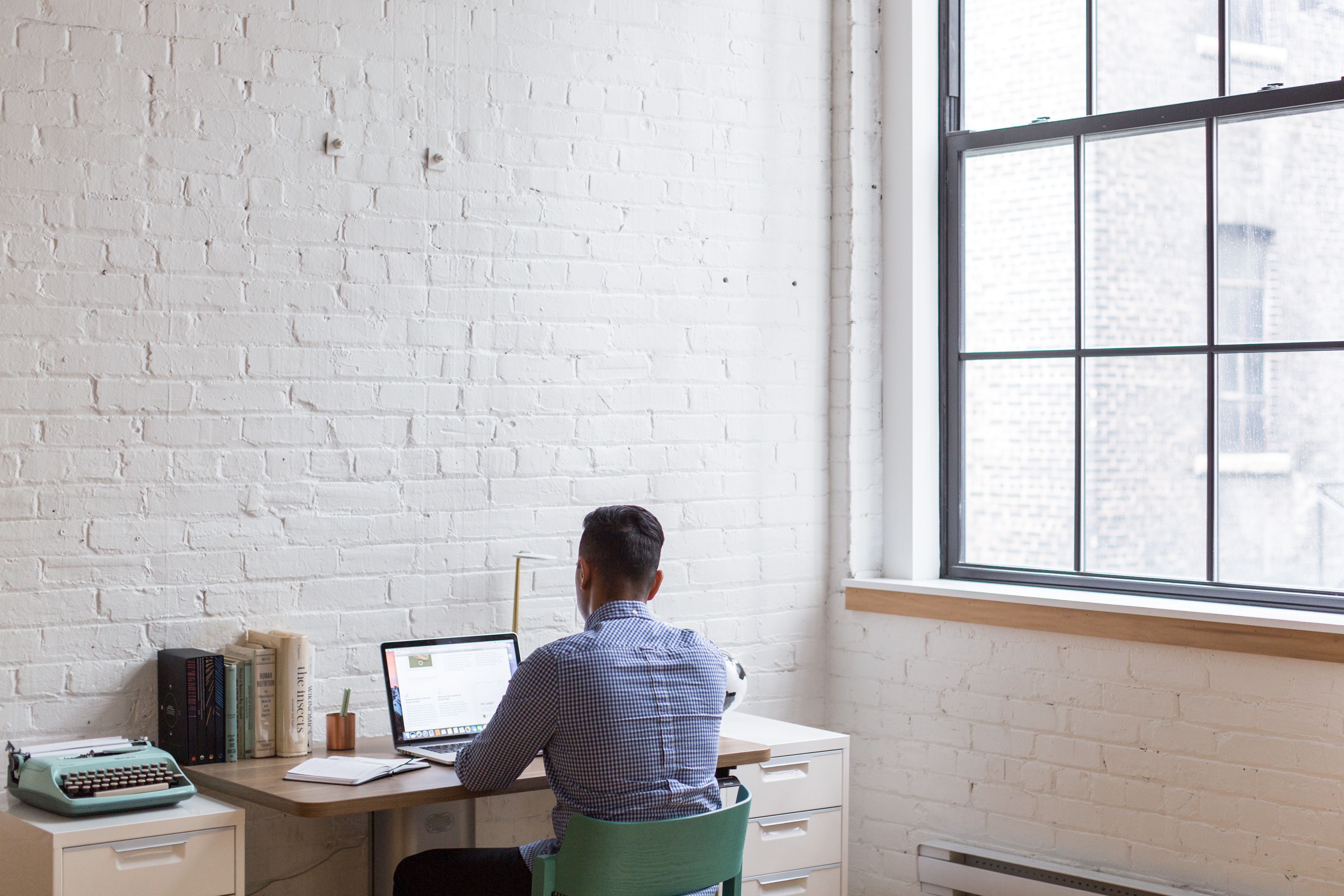 man facing wall working at desk