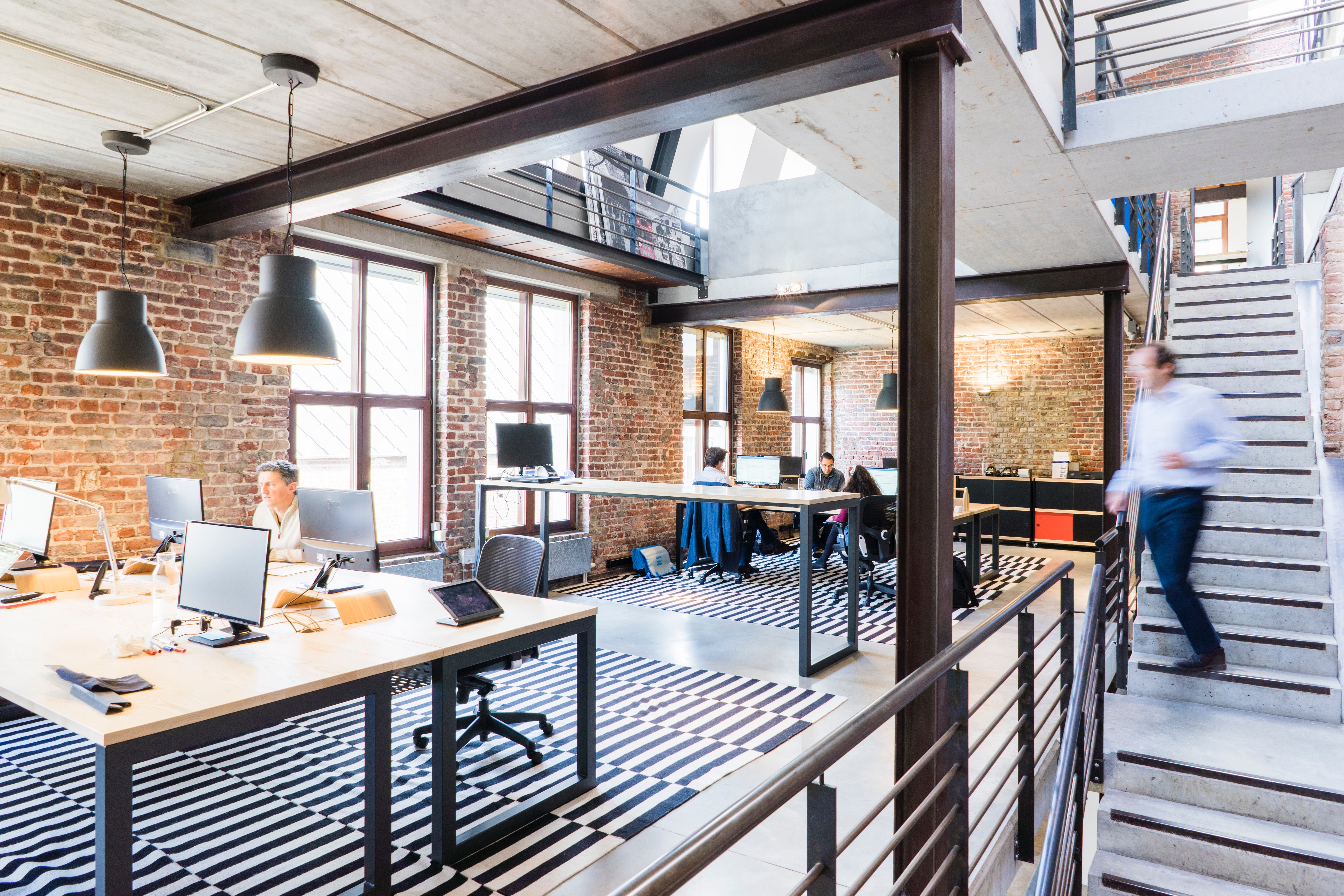 An open-format office with people working and a man descending a staircase