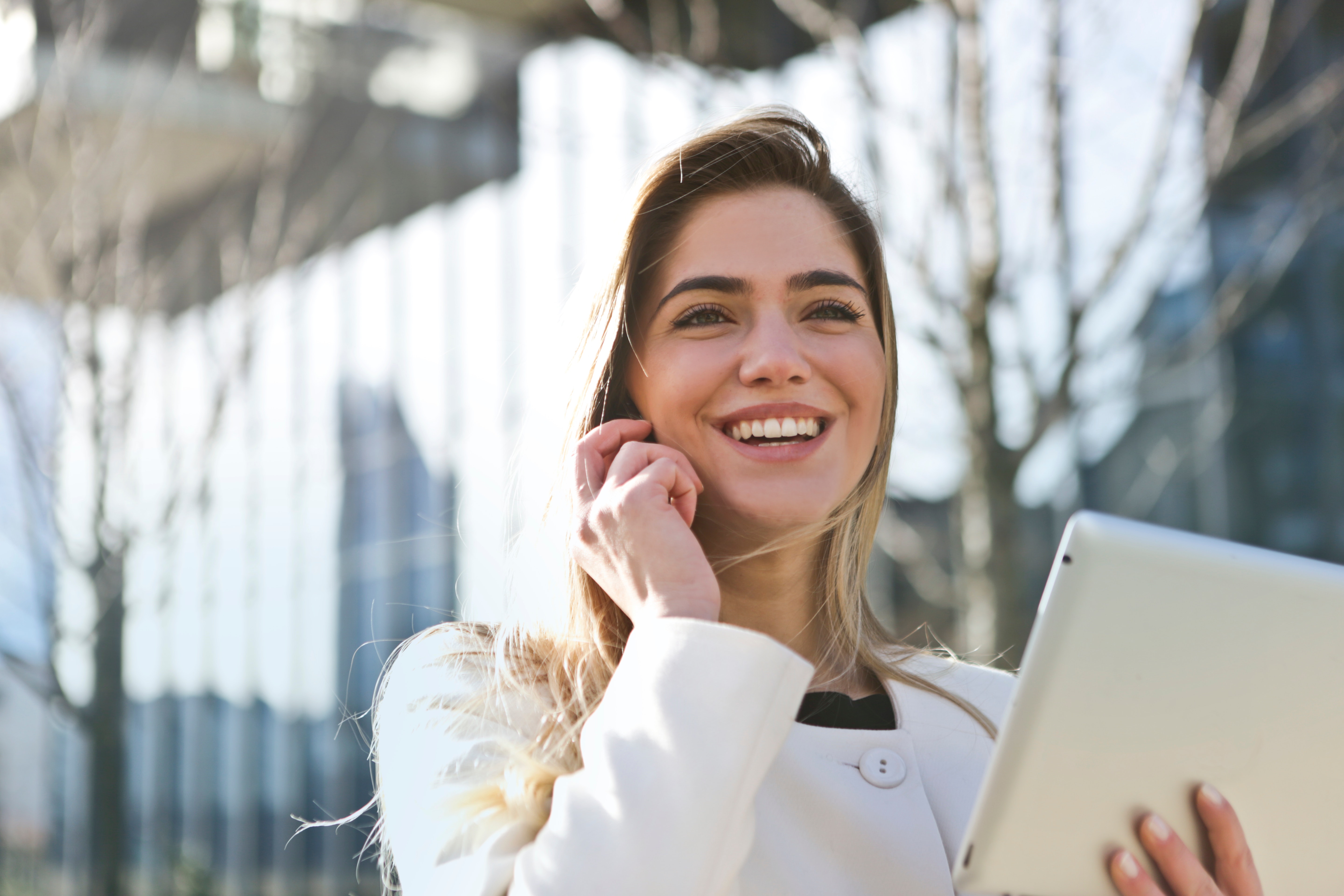 smiling woman holding a tablet while taking a phone call