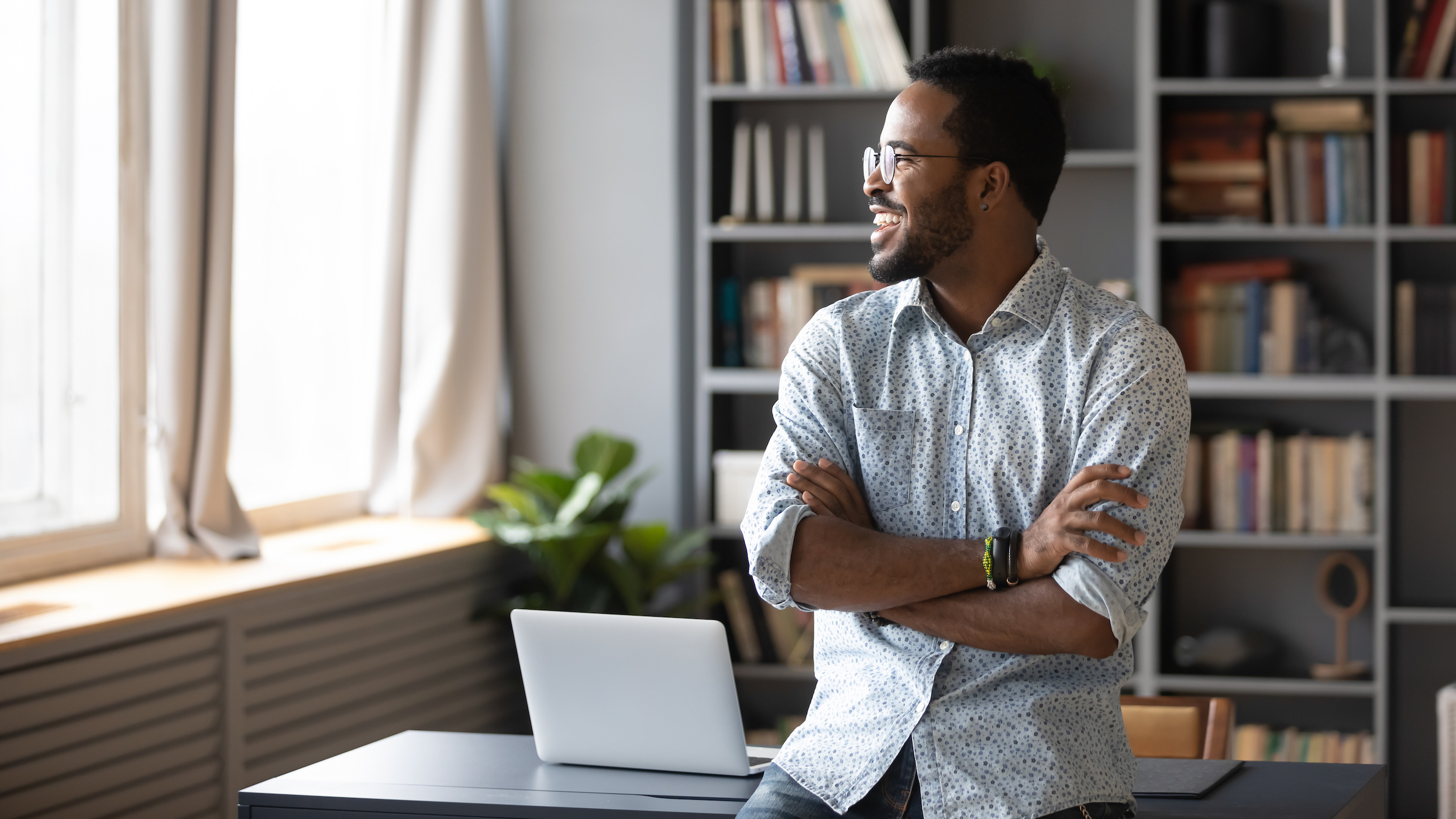 A Black employee looking away dreaming standing in office